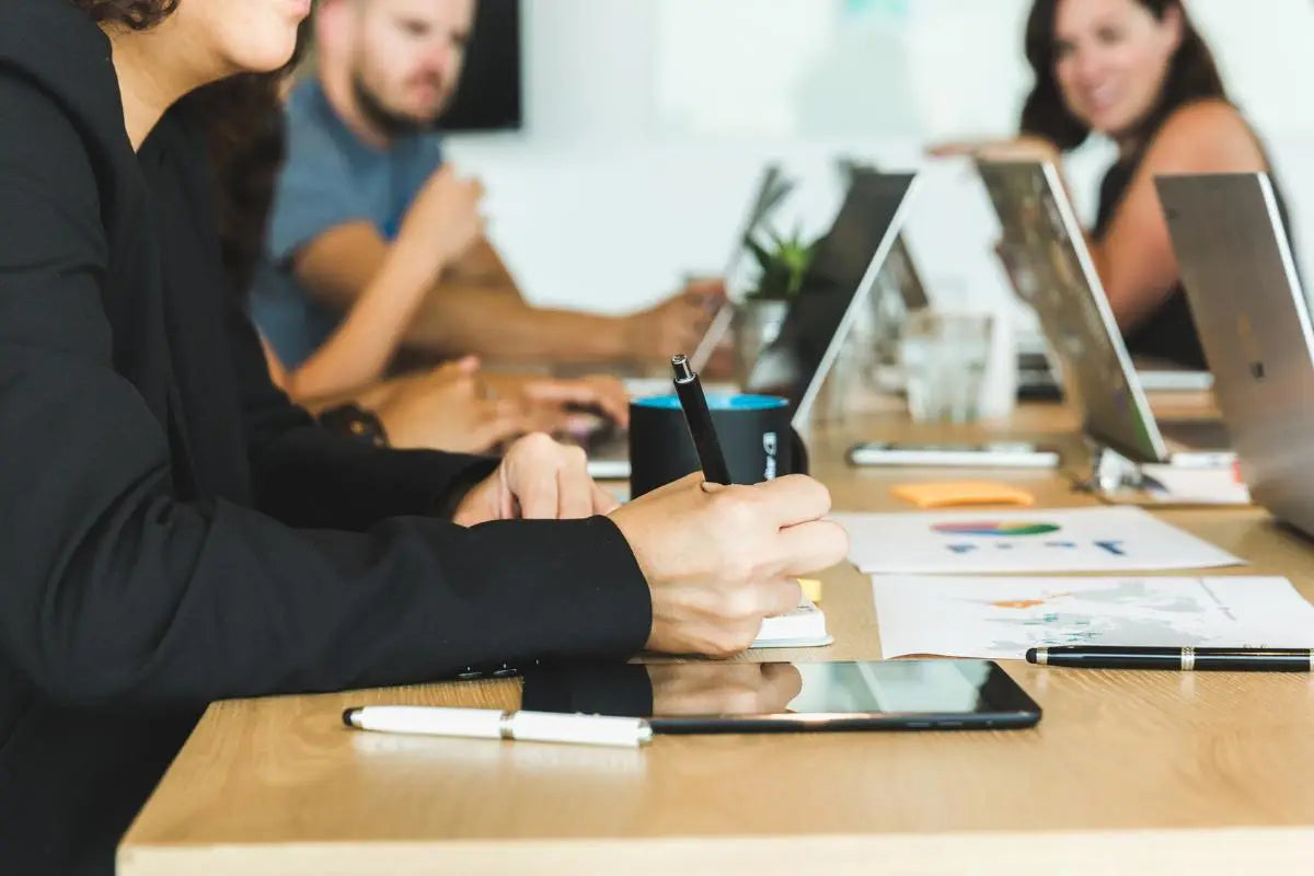Woman taking notes during a collaborative team meeting representing North Ember’s operational support services focused on efficiency, scalability, and process improvement.